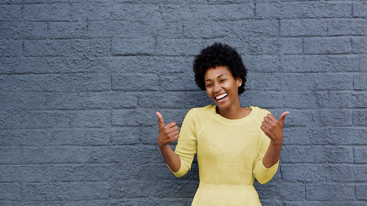 happy, smiling woman with two thumbs up excited about the affordable cost of RCI's relationship coach training
